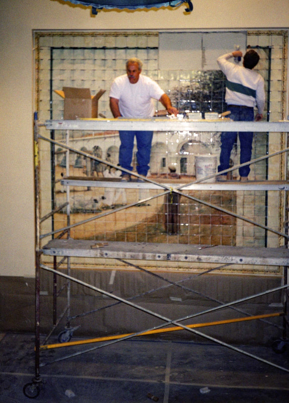 Tile Setters nearly finished setting the 600 tiles to the wall to the recessed wall in the lobby of the San Juan Medical Facility, San Juan Capistrano, CA. Tile setters  installing the Mission San Juan Capistrano Mural" by artist Jamie Santaniello on scaffolding in the year 2000.